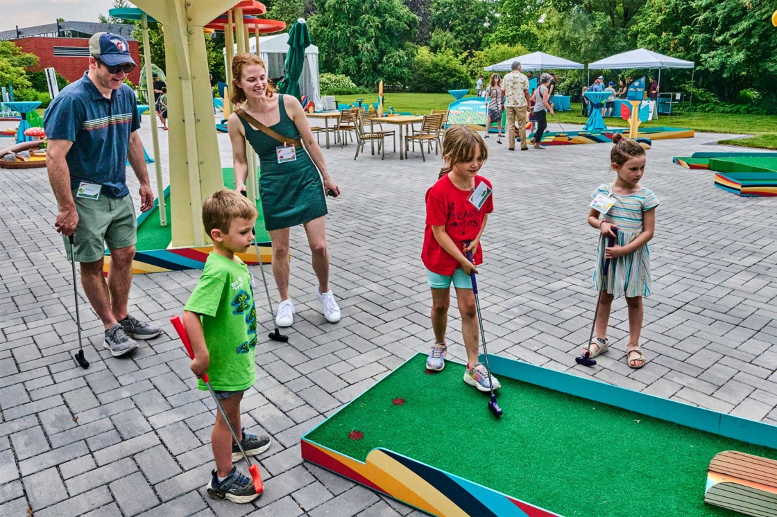 A family cheer for each other while playing mini golf.