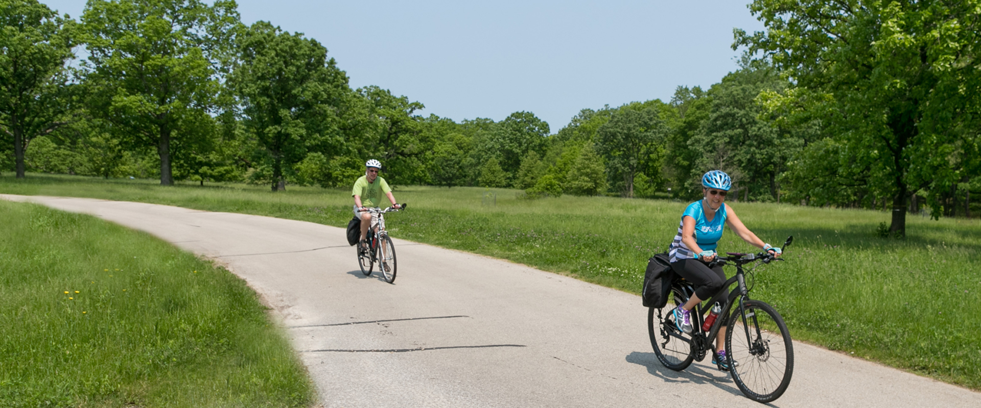 Photograph of two visitors biking on a paved trail at The Morton Arboretum