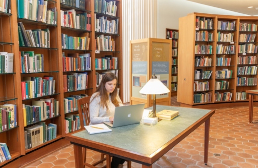 A person sitting at a table, working on a computer in the Sterling Morton Library.