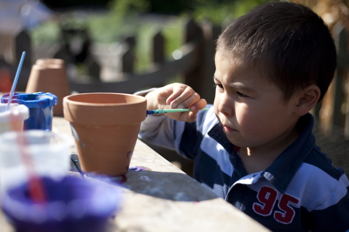 Young boy painting a flower pot in the Children's Garden