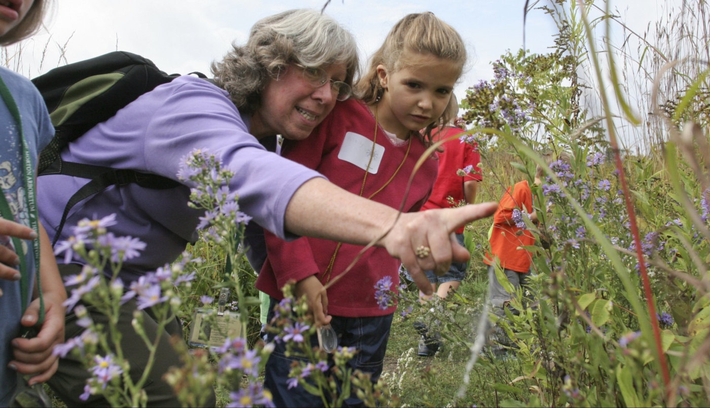 Student looks at spider with teacher