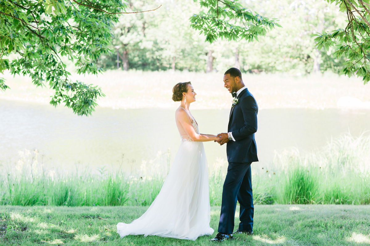Wedding couple pose by meadow lake