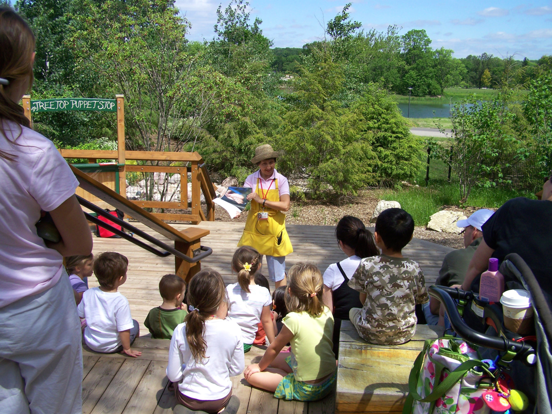 A group of parents and children gathered for story time in the Children's Garden