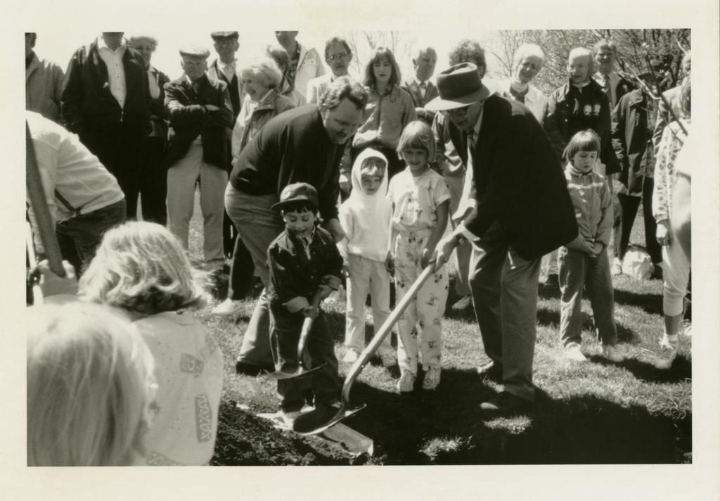 Historic image of men planting a tree with children