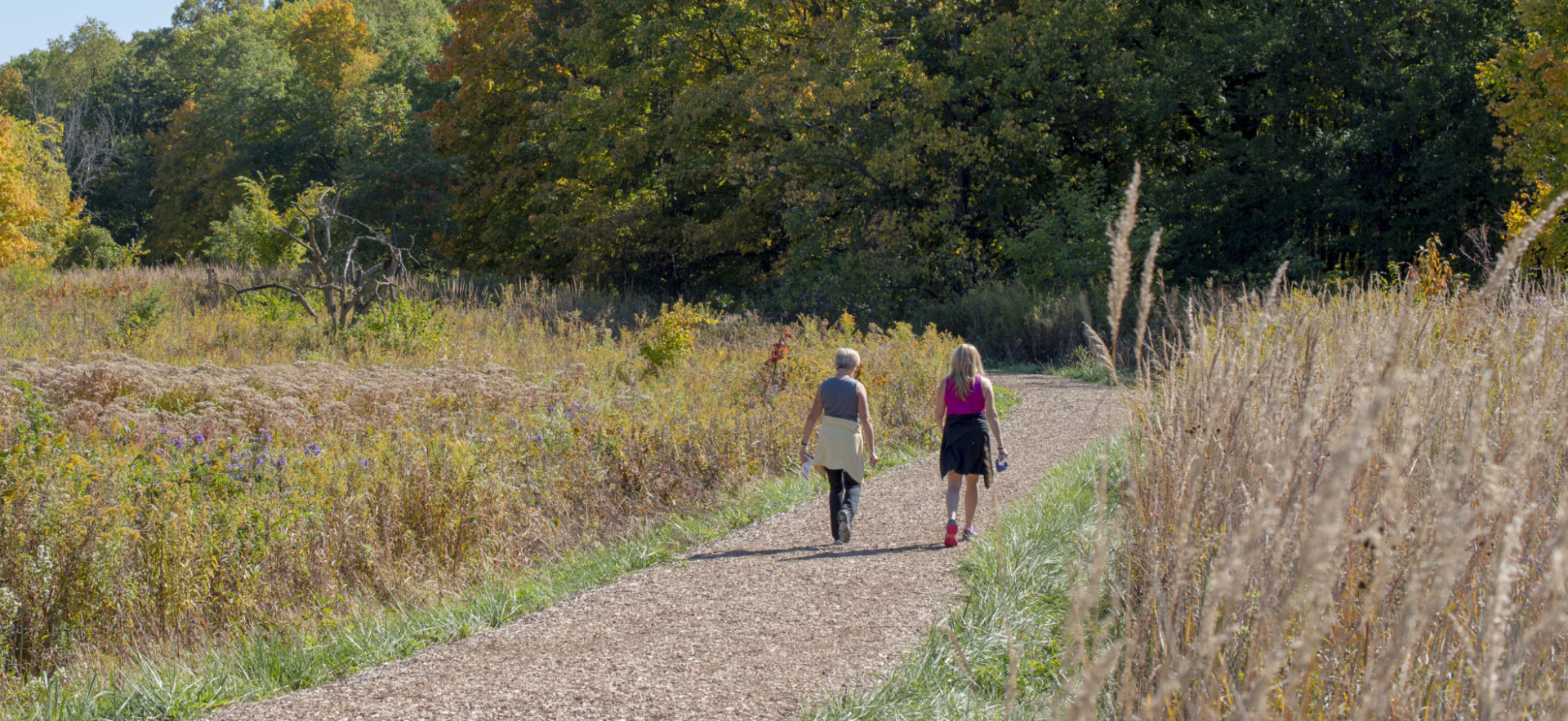 Two ladies walking along a path in early fall.