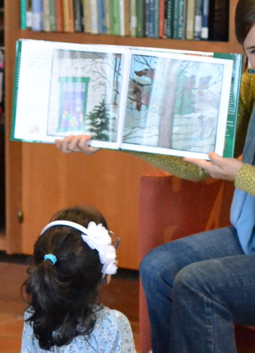 Adult reads a book to children in the library