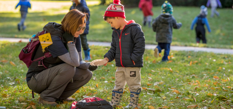 A child works with a teacher to learn types of leaves.