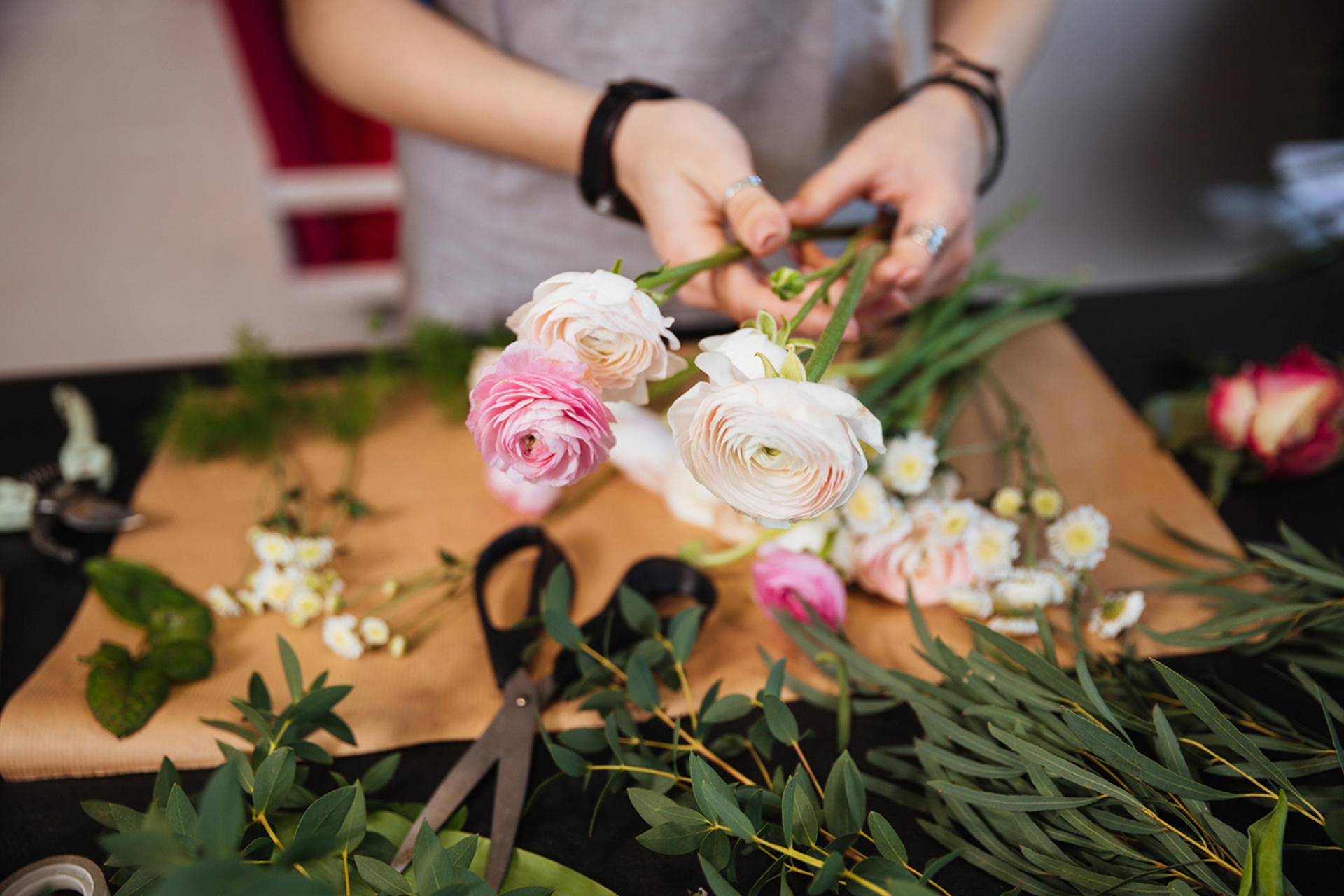 A woman cutting flowers to create a floral arrangement