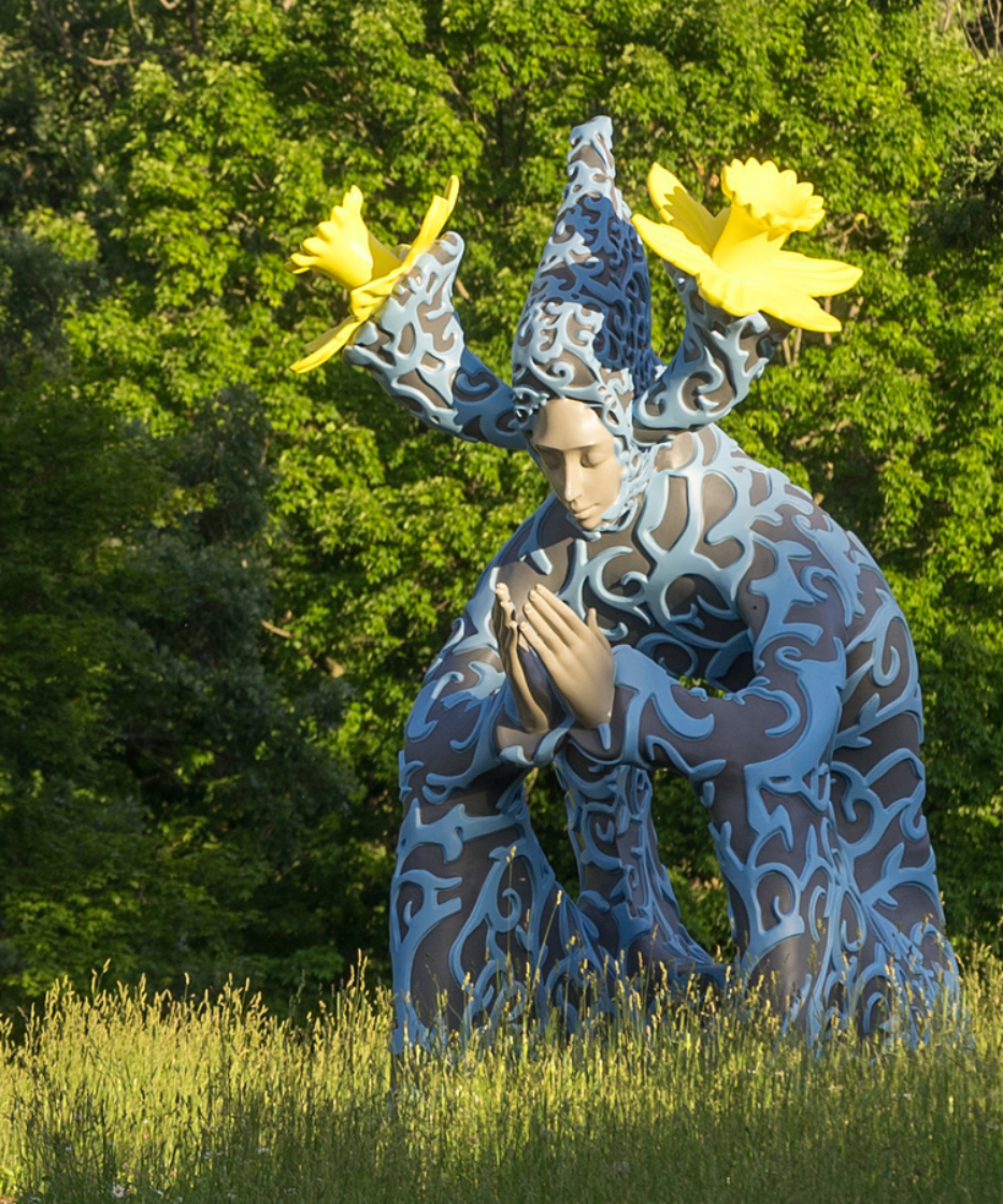 Ephemera Human Nature sculpture with tall grass around it surrounded by trees in the summer