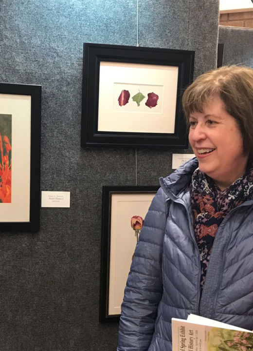 Two women admire paintings at the Nature Artists Guild exhibit