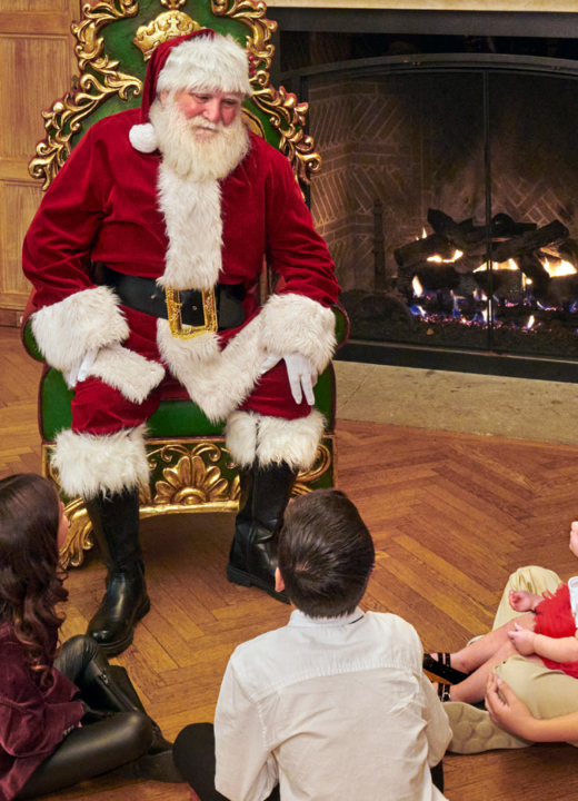 Santa gathers around children and a fireplace