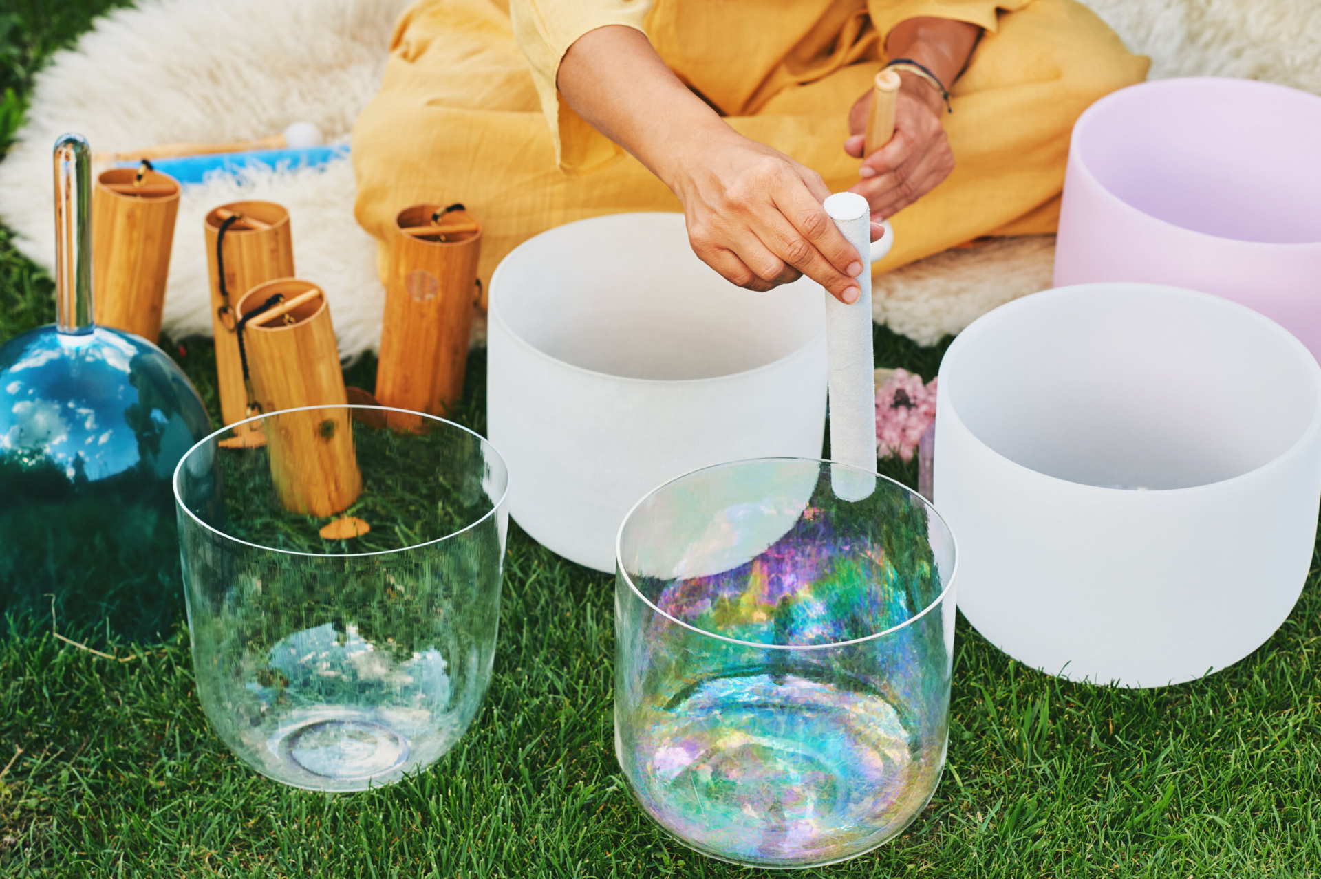 A woman playing an arrangement of crystal bowls used in sound meditation.