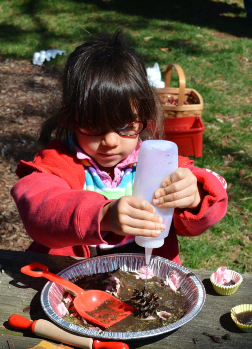 A child making a mud pie on a picnic table.