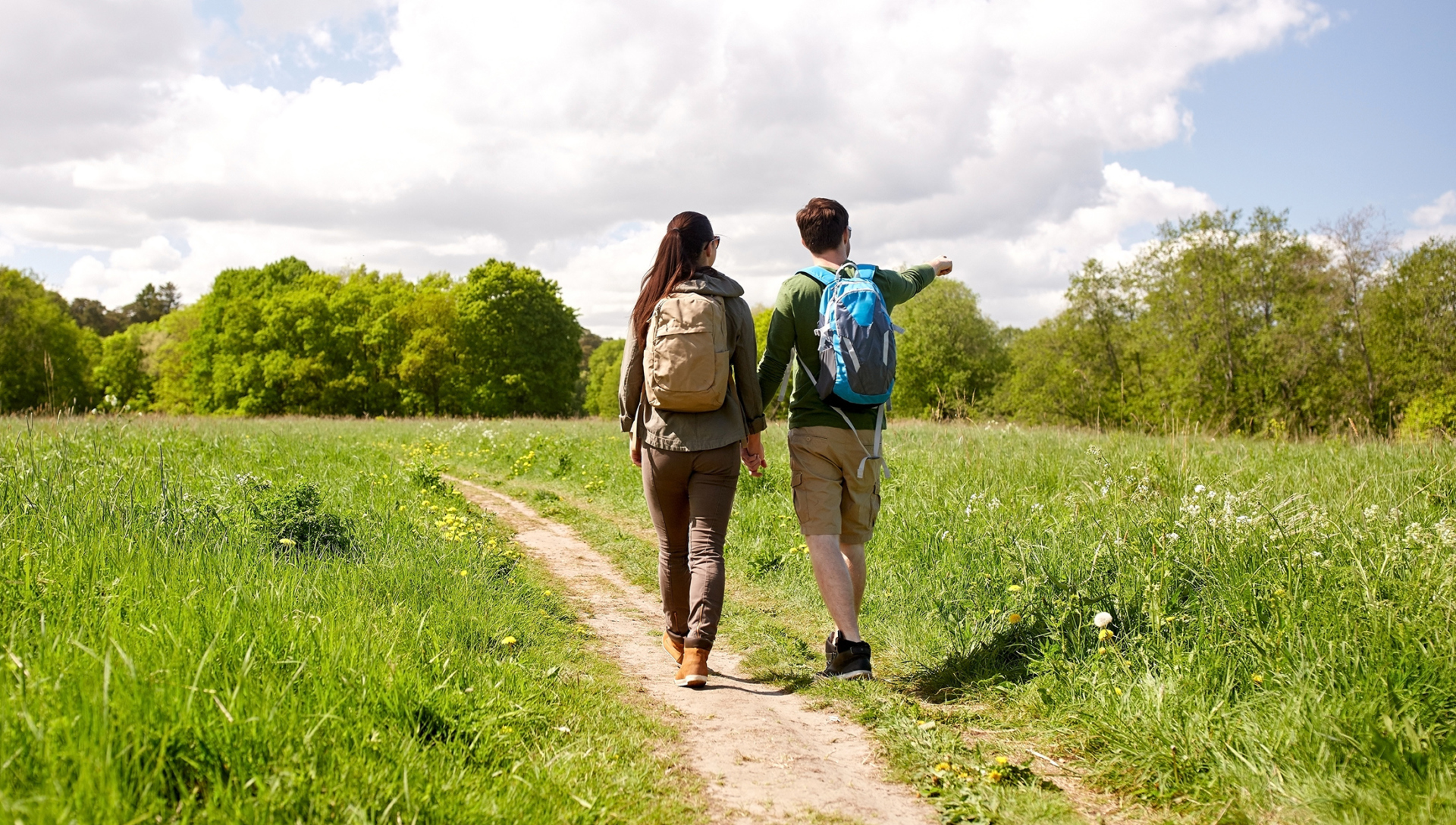 A couple backpacking along a trail, pointing at something in the distance.