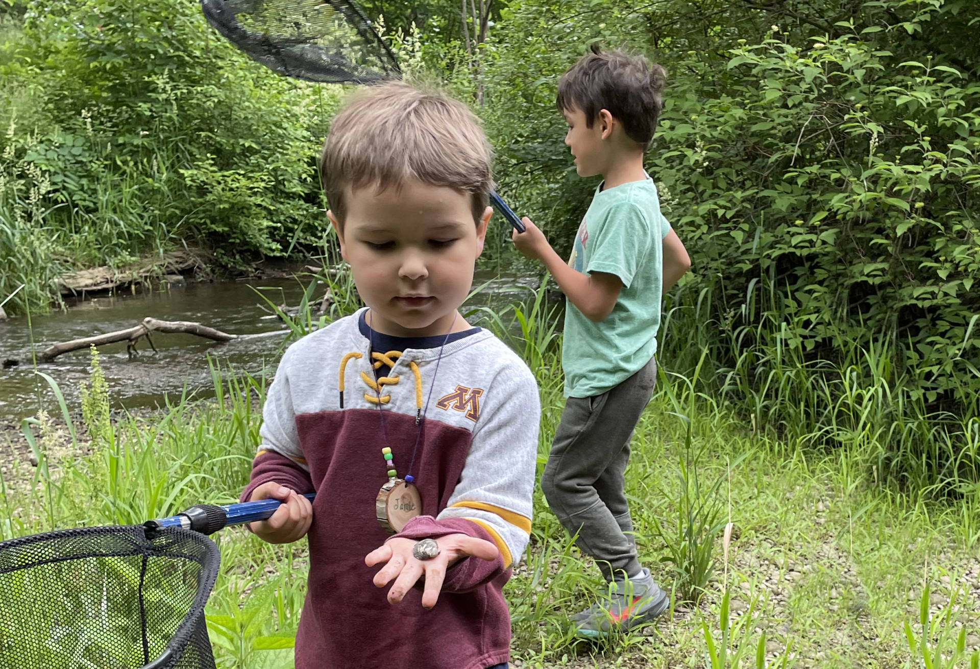 Young boys exploring the woods and creeks with nets in spring