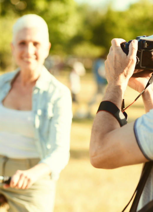 A man with a professional camera taking a photo of a woman on a bike outdoors.