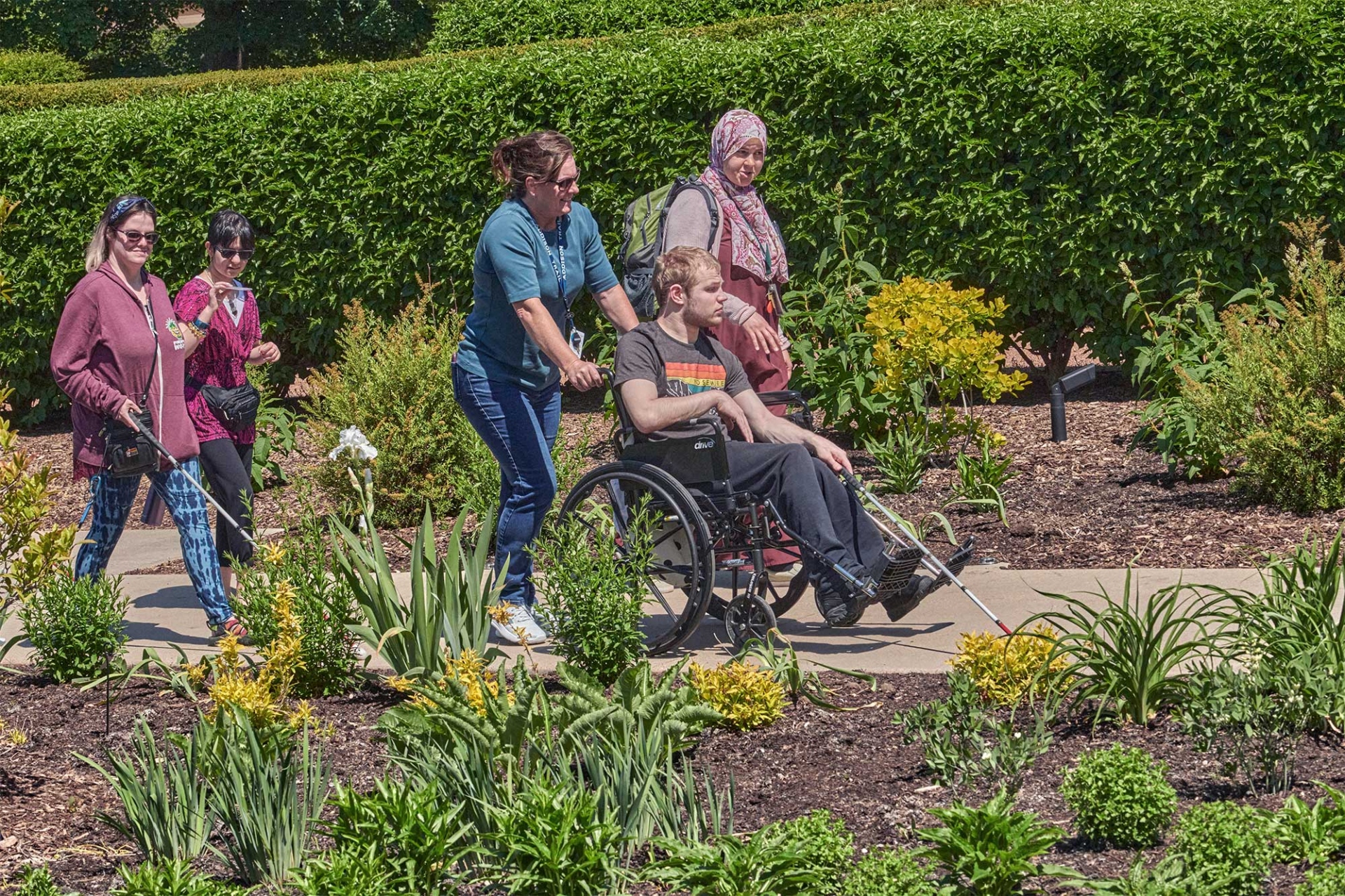 A group of vision impaired guests walk through The Gerard T. Donnelly Grand Garden with an Arboretum lead