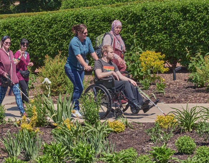 A group of vision impaired guests walk through The Gerard T. Donnelly Grand Garden with an Arboretum lead
