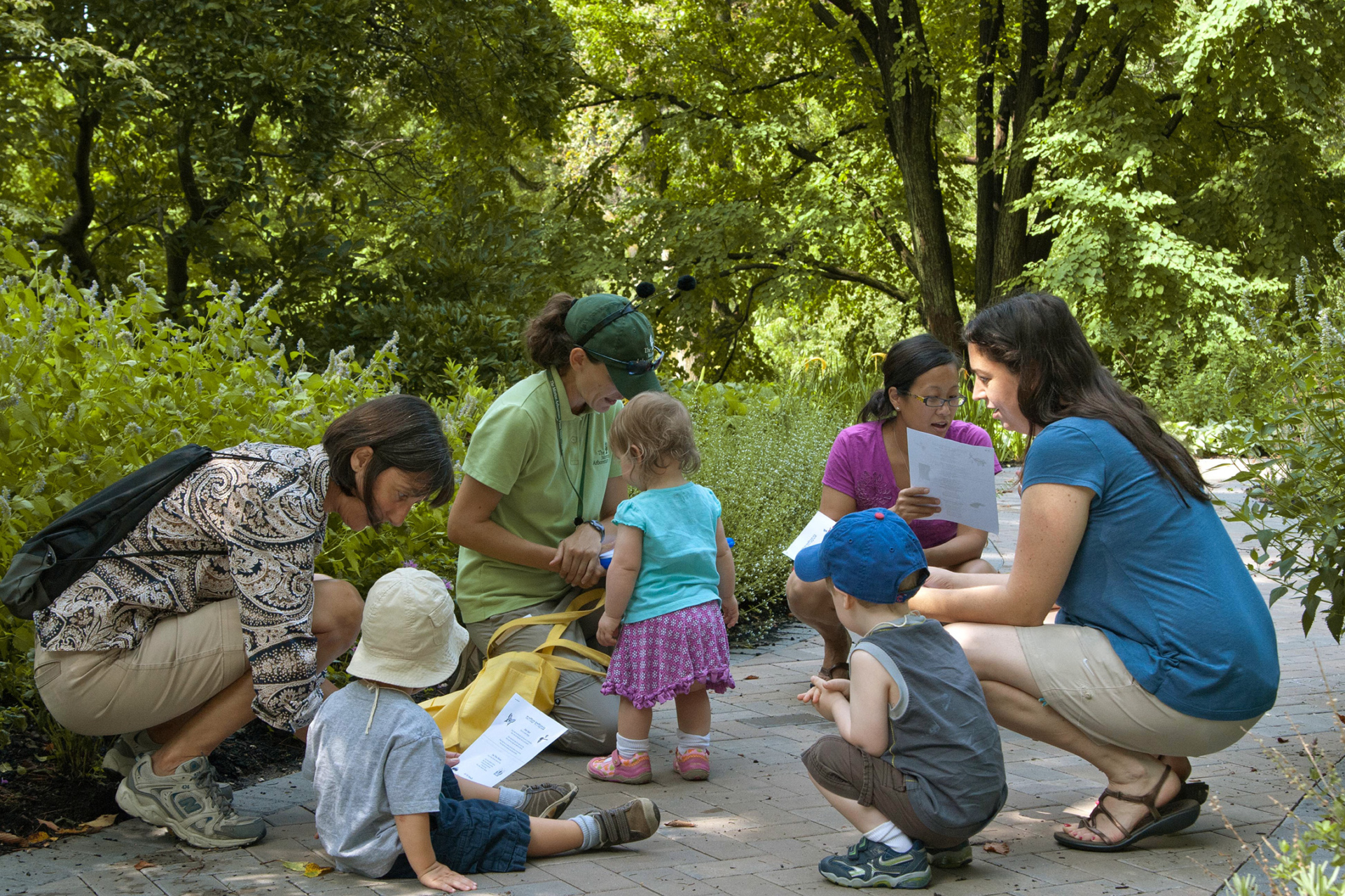 A group of moms and toddlers taking a class outdoors in the Children's Garden