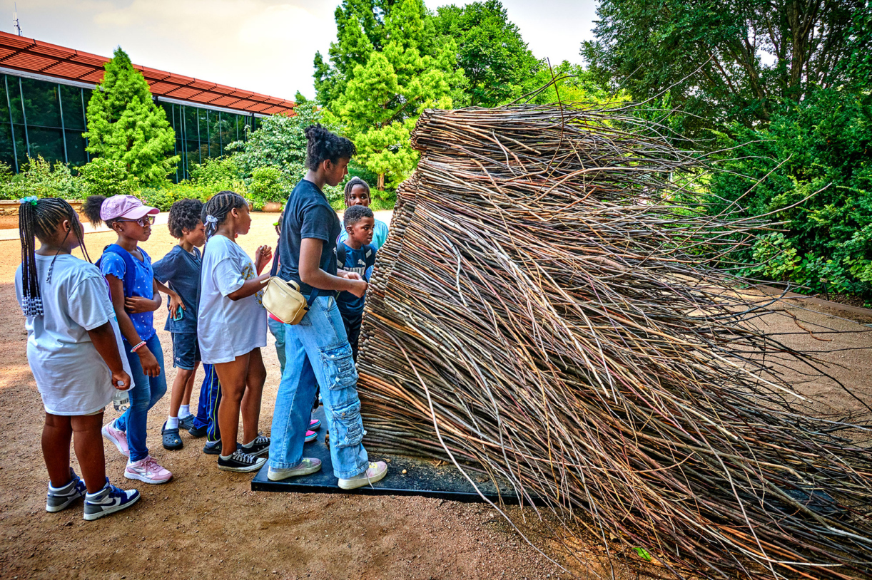 A group of kids look closely at Stillness in Motion, an Of the Earth sculpture in Arbor Court