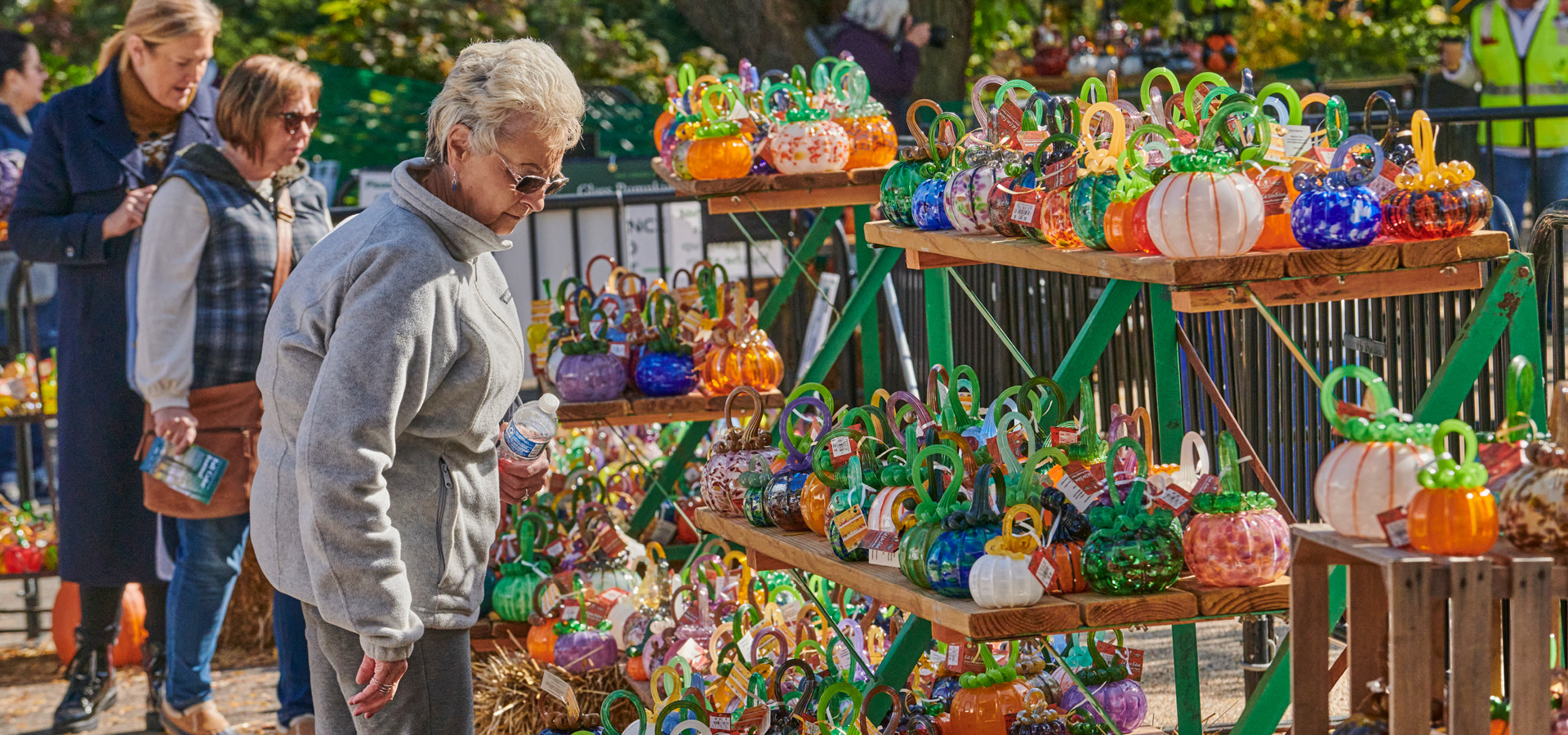 A guest admires all of the beautiful glass pumpkins available to purchase