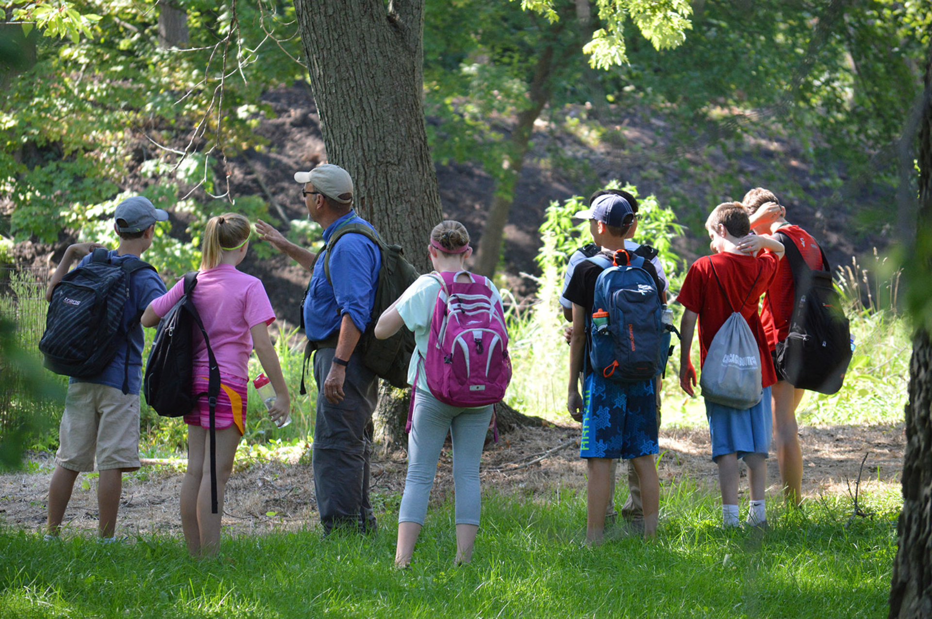 A group of middle school students outside with an instructor, learning about trees.