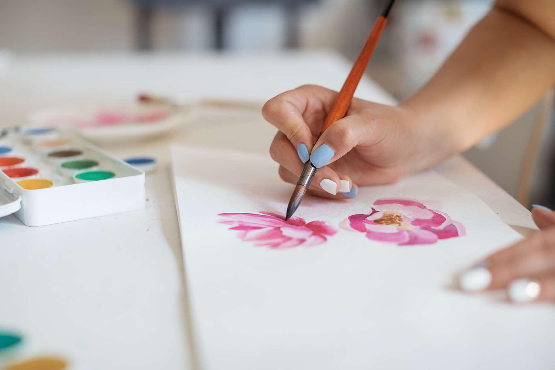 An unidentified artist painting pink flowers with gouache.