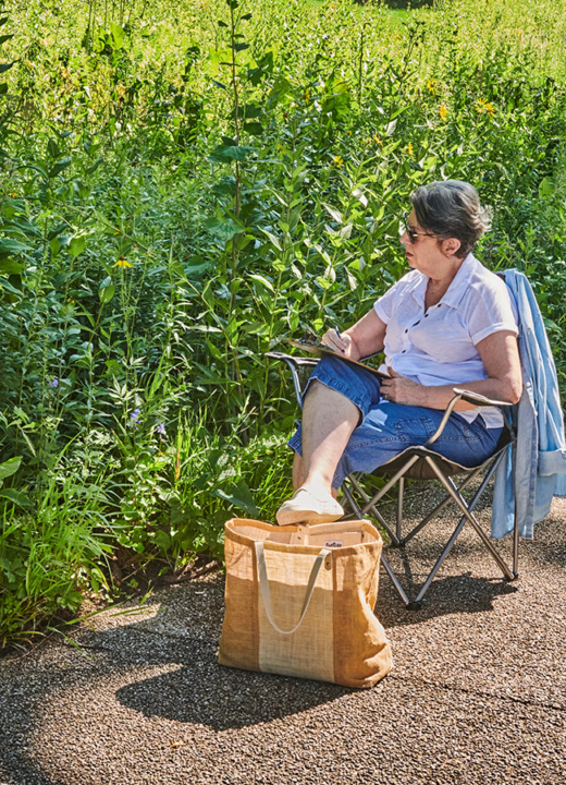 A woman working on a drawing outside in the Schulenburg Prairie
