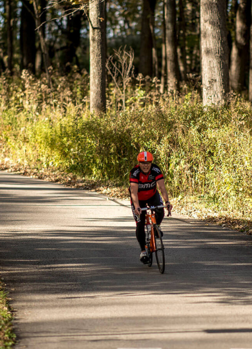 Photograph of cyclist biking on the paved roads of The Morton Arboretum's East Side