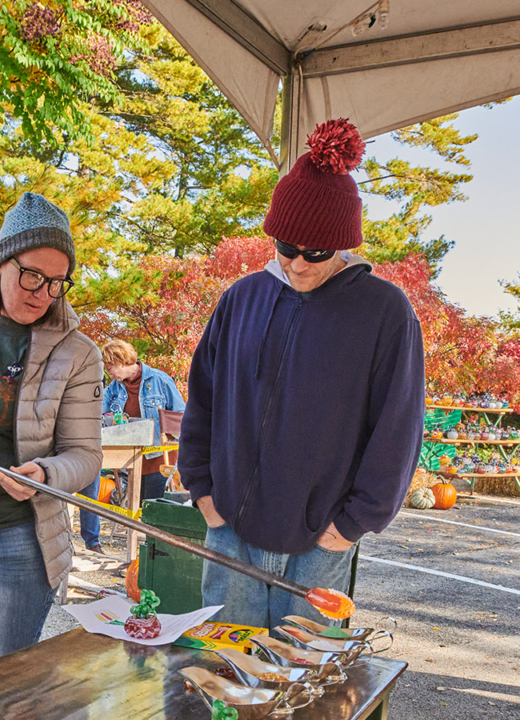 A group of visitors watches a glass blowing demonstration from artists at The Morton Arboretum's Glass Pumpkin Patch