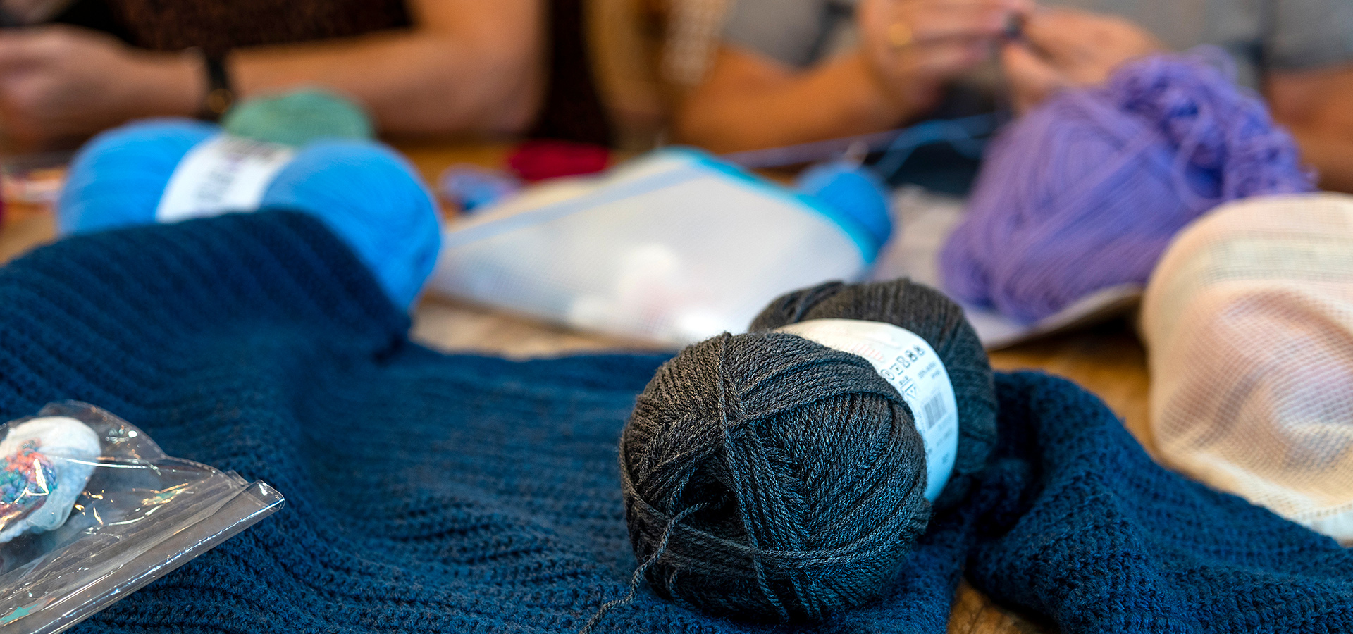 A photograph showing different types of yarn and fiber arts supplies on a work table