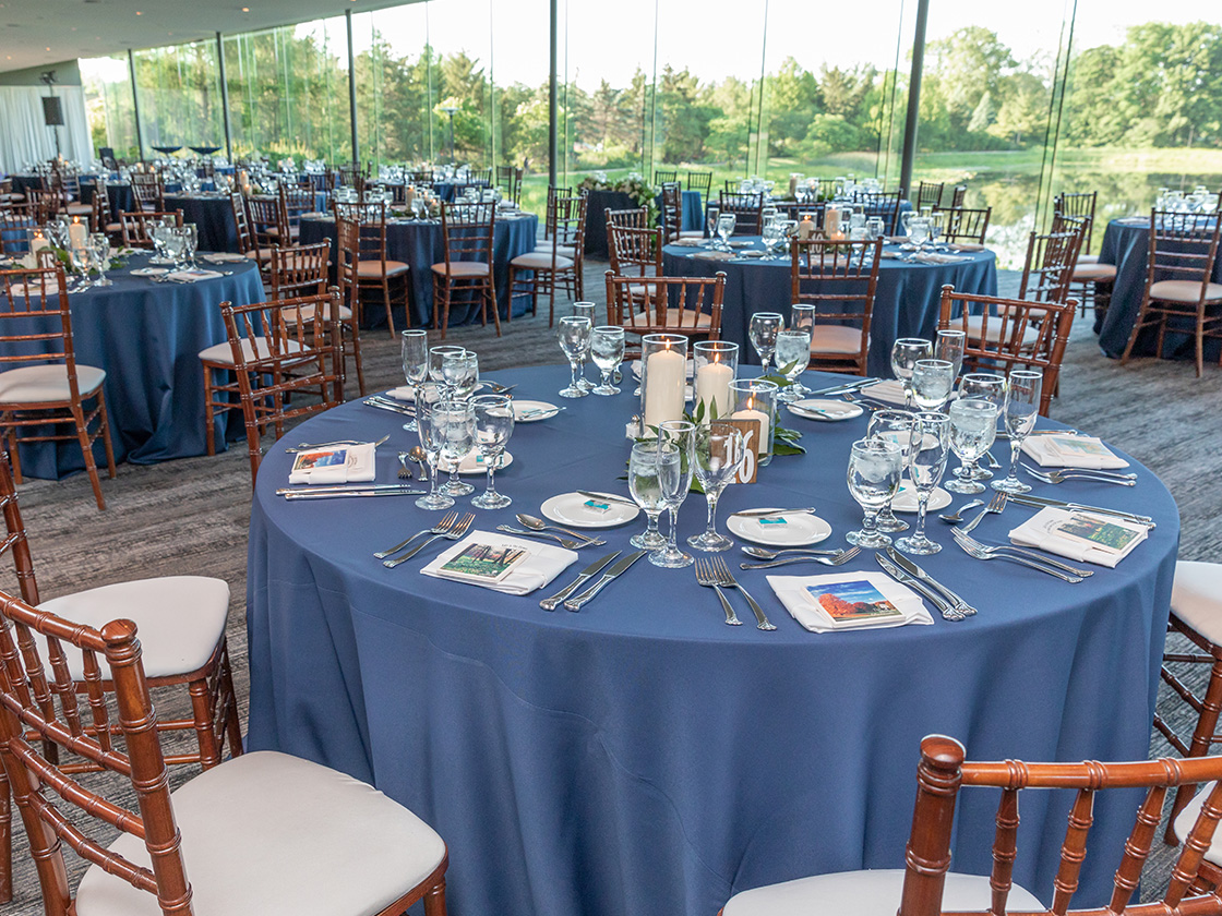 Dinner tables with blue tablecloths and candles in the Ginkgo Room