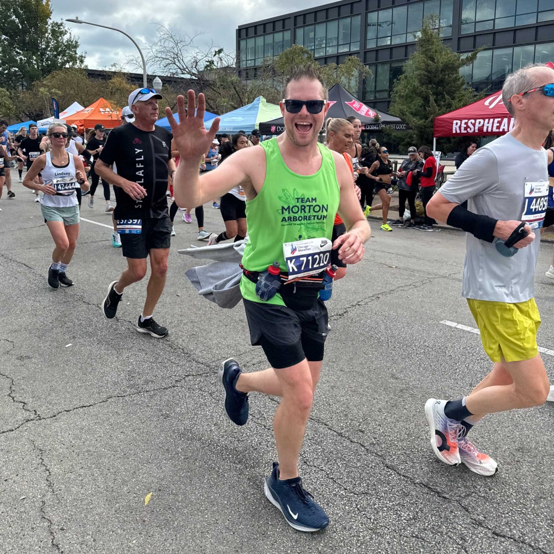 Runner in Team Morton Arboretum tank top waving to the camera