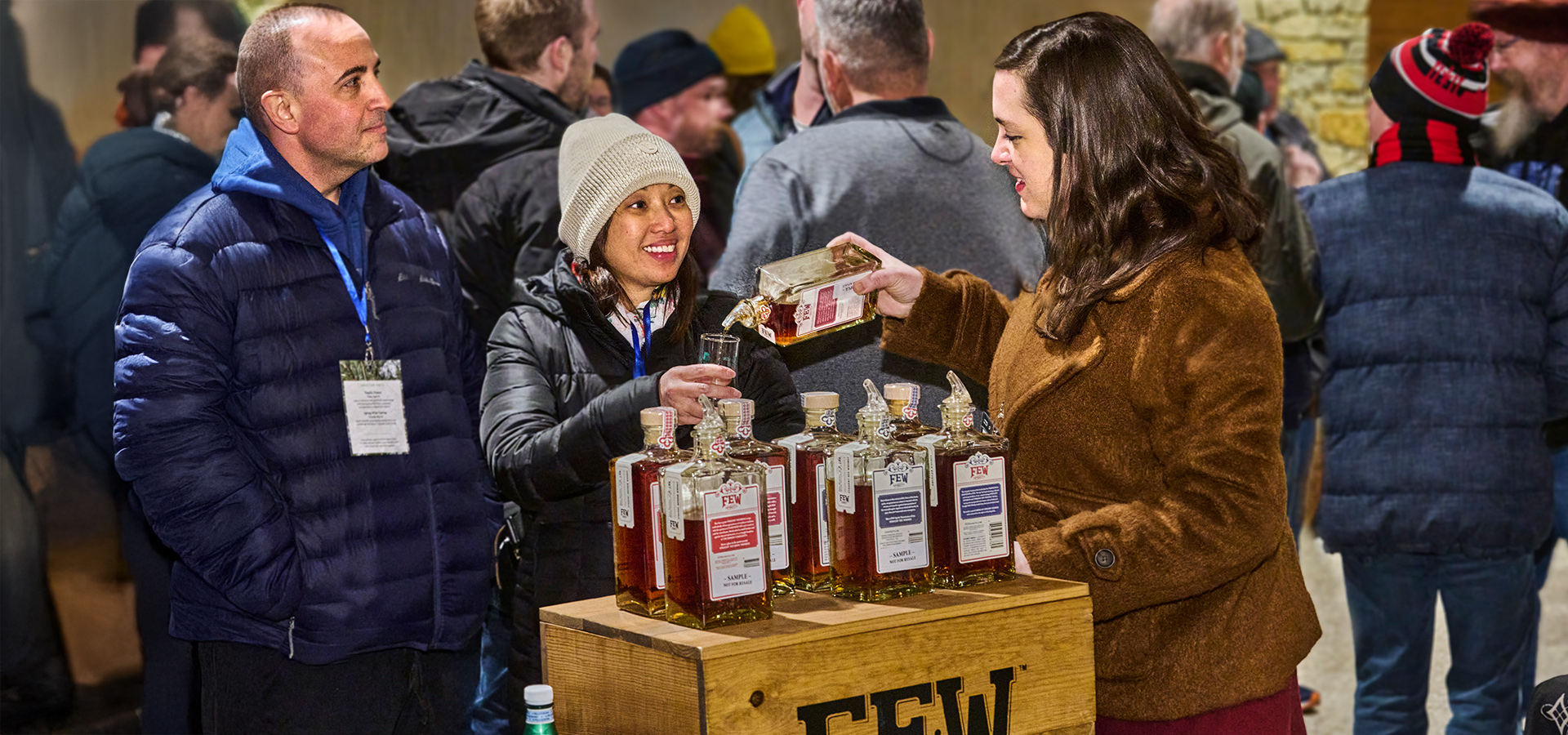 Photograph of visitors enjoying a sample of whiskey poured by an employee at the Whiskey Tasting at the Firefly Pavilion