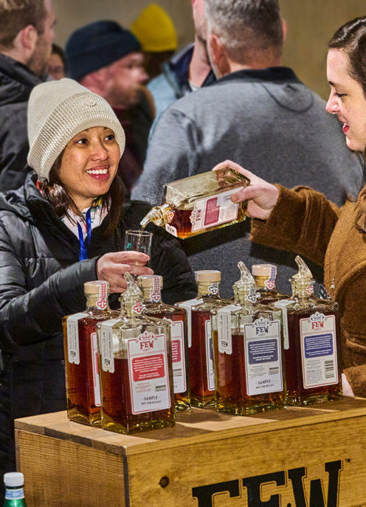 Photograph of visitors enjoying a sample of whiskey poured by an employee at the Whiskey Tasting at the Firefly Pavilion