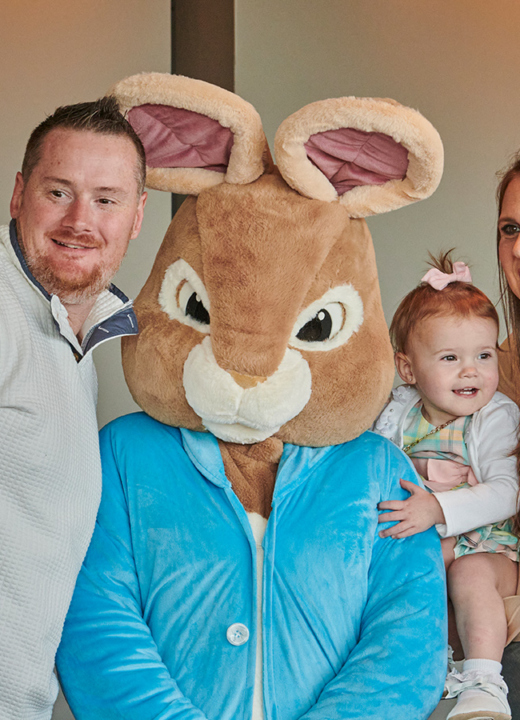 A family posing with the Easter Bunny while someone takes a photo with their phone in the Ginkgo restaurant during the Breakfast with the Bunny event.