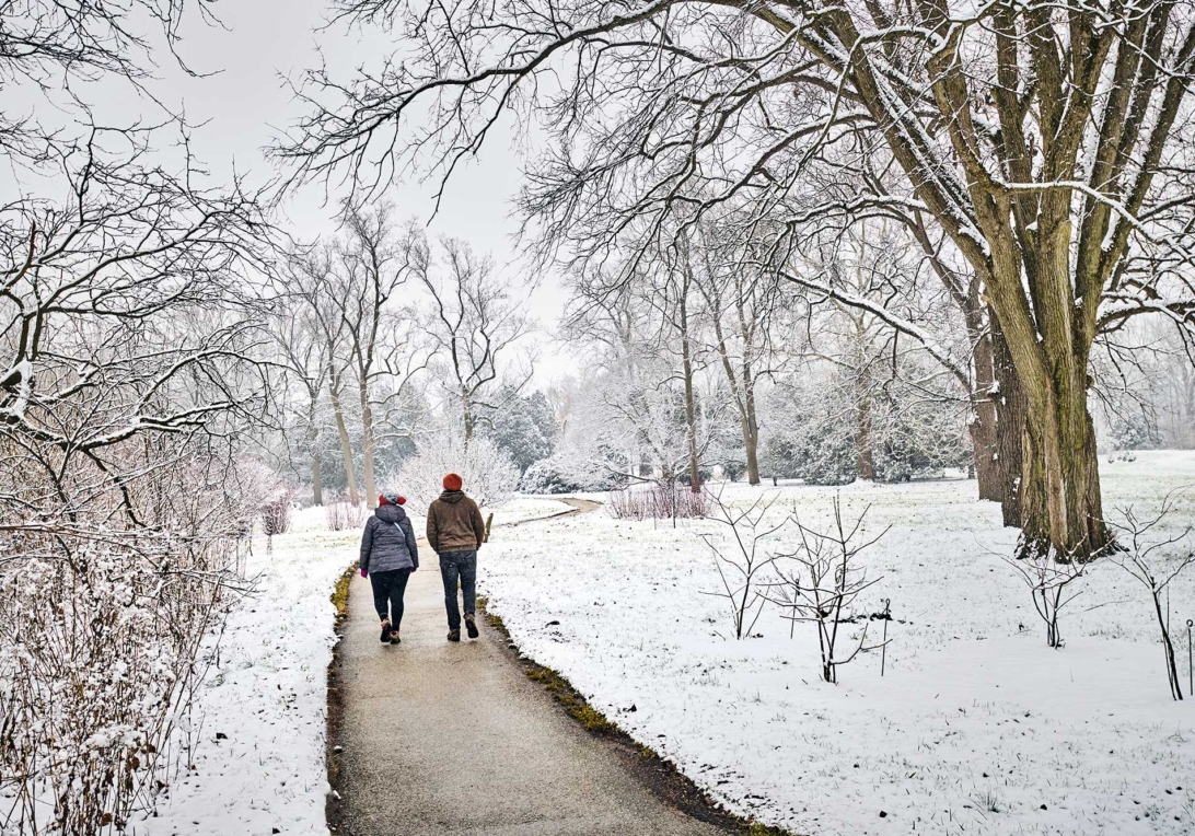 A couple walk along Joy Path after a fresh dusting of snow in winter.