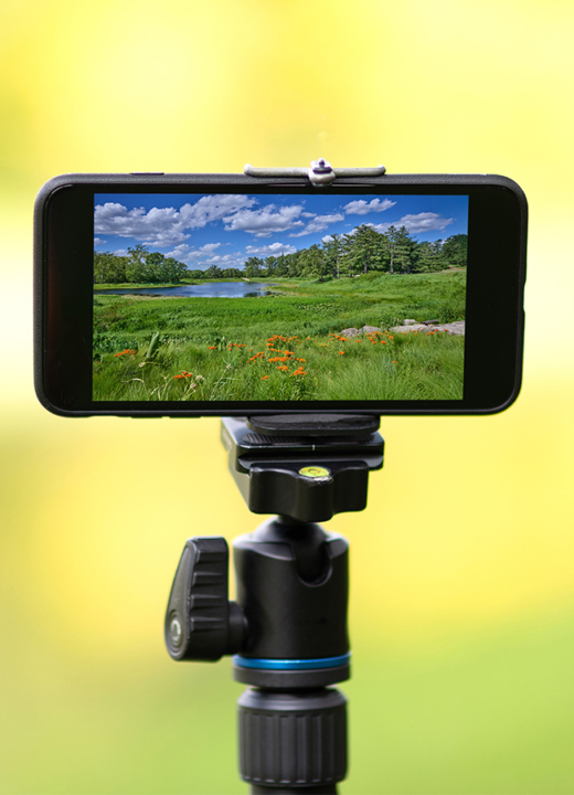 An iphone attached to a tripod set against a blurred background. On the screen is Meadow Lake about to be photographed.