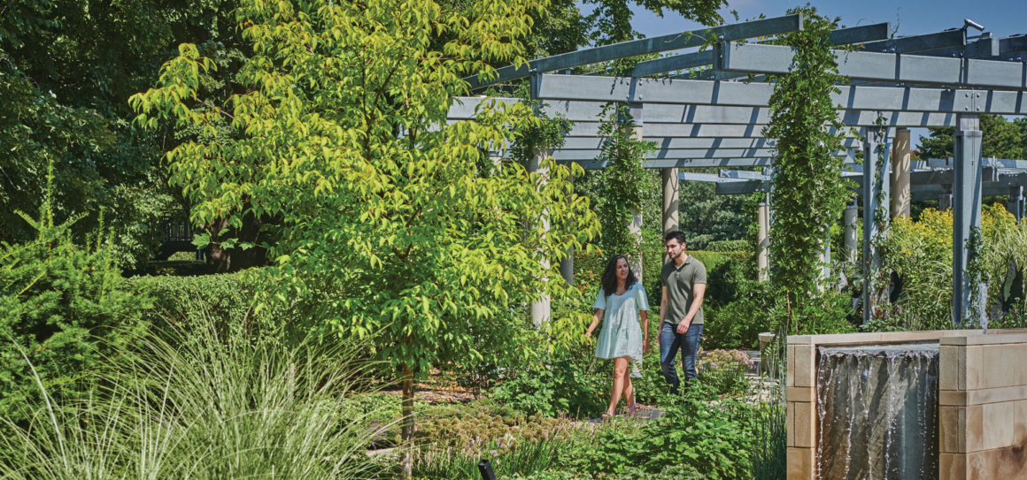 Photograph of a young couple walking through a beautiful tree-filled garden