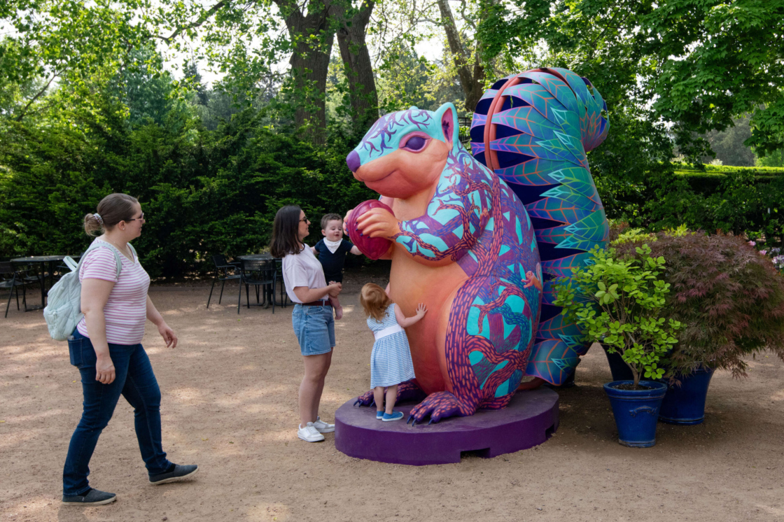 Two adults and two small children approach and touch Scamp the squirrel