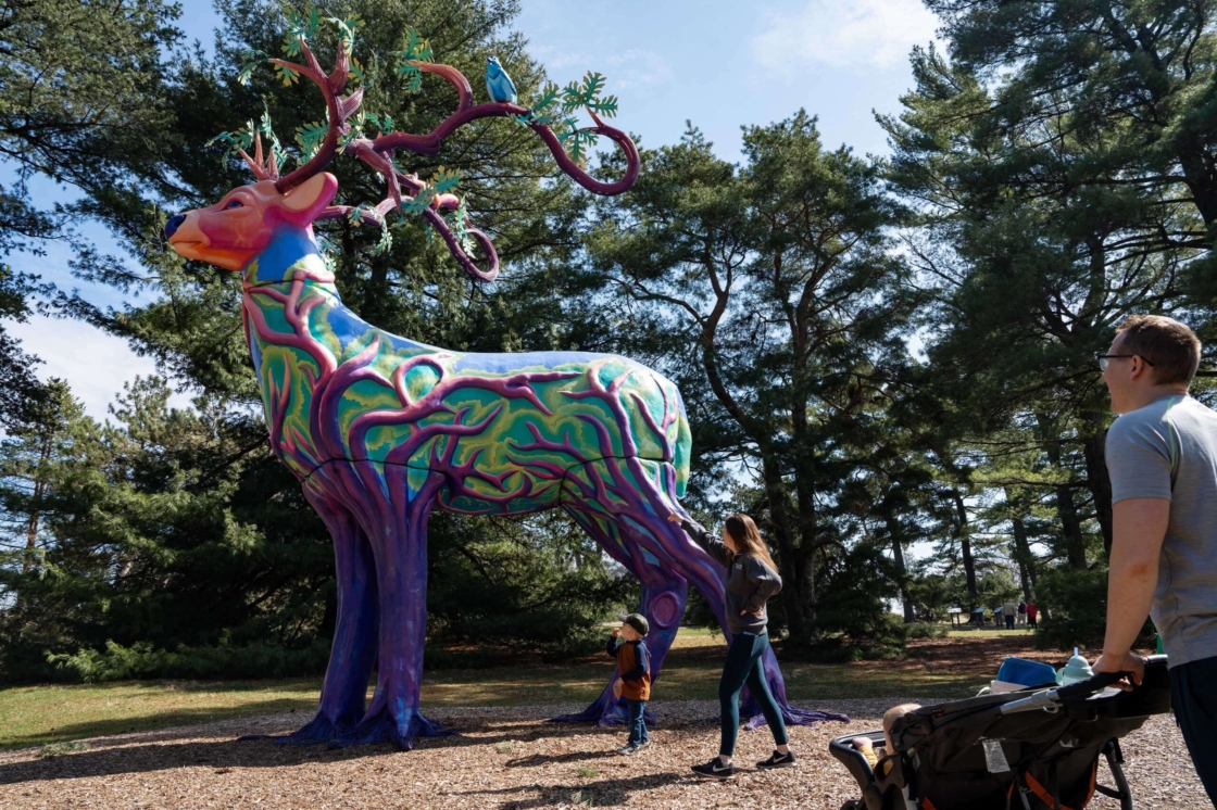 Colorful, 17-foot sculpture of a deer with roots for legs and antlers like oak branches