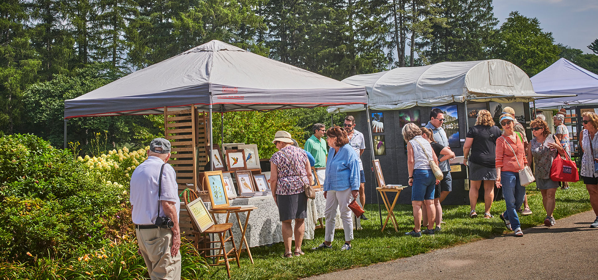 Guests look at artworks displayed in tents during The Morton Arboretum's Wine and Art Walk.