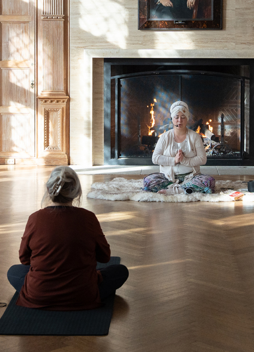 Photograph of yoga participants and a yoga teacher meditating in front of a fireplace in the historic Thornhill Education Center at The Morton Arboretum