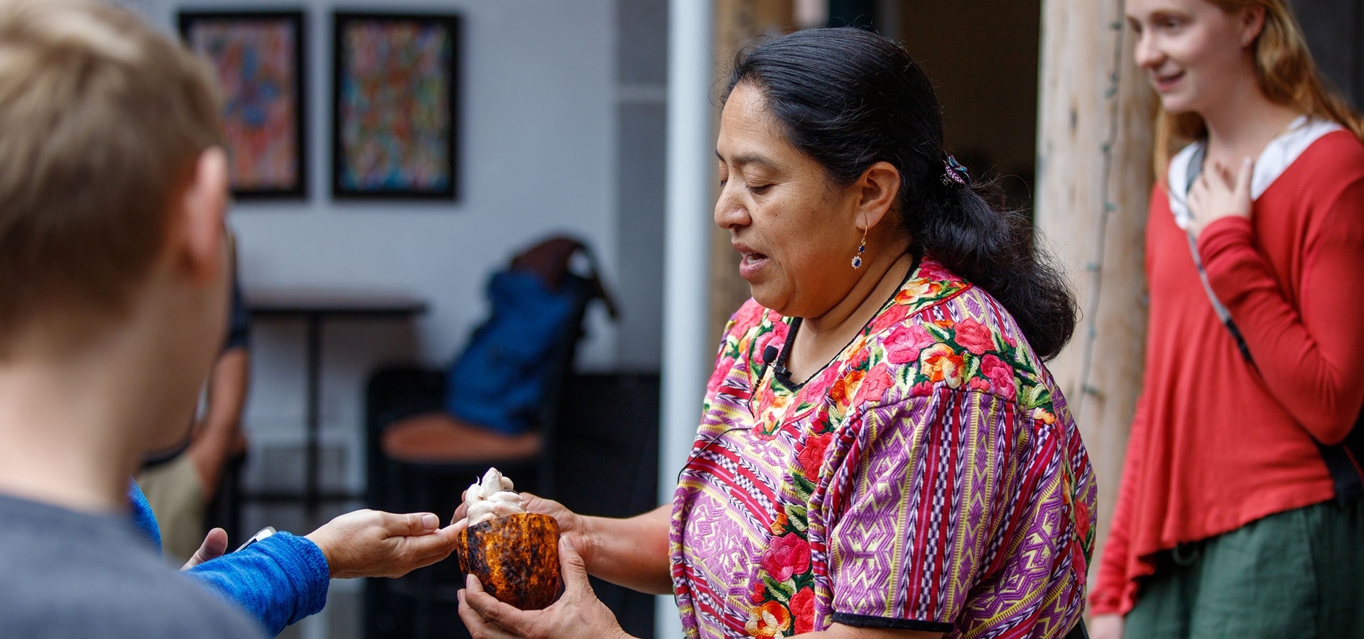 Photograph of a woman holding a raw cacao bean pod in an education demonstration