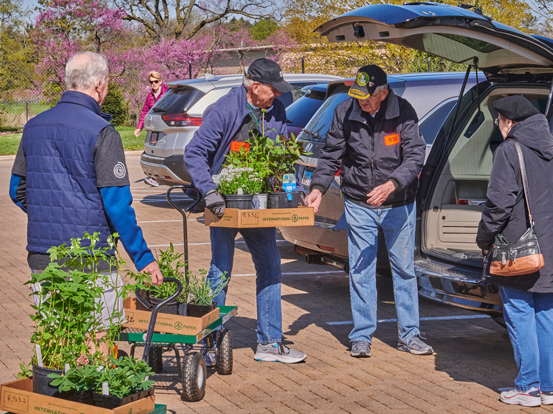 Photograph of arboretum volunteers assisting a customer loading plants into their car