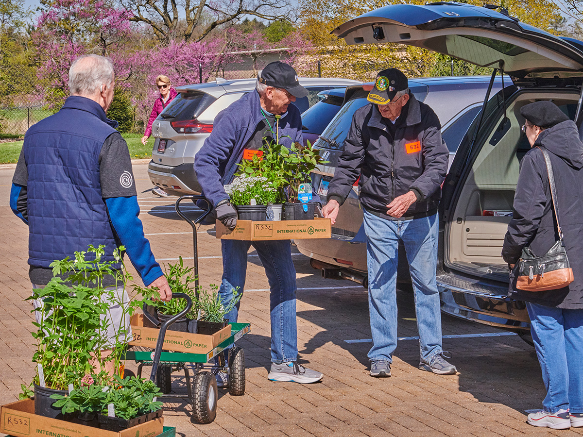 Photograph of arboretum volunteers assisting a customer loading plants into their car