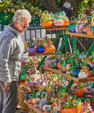 Photograph of an older woman visitor shopping for glass pumpkins at the Glass Pumpkin Patch at The Morton Arboretum