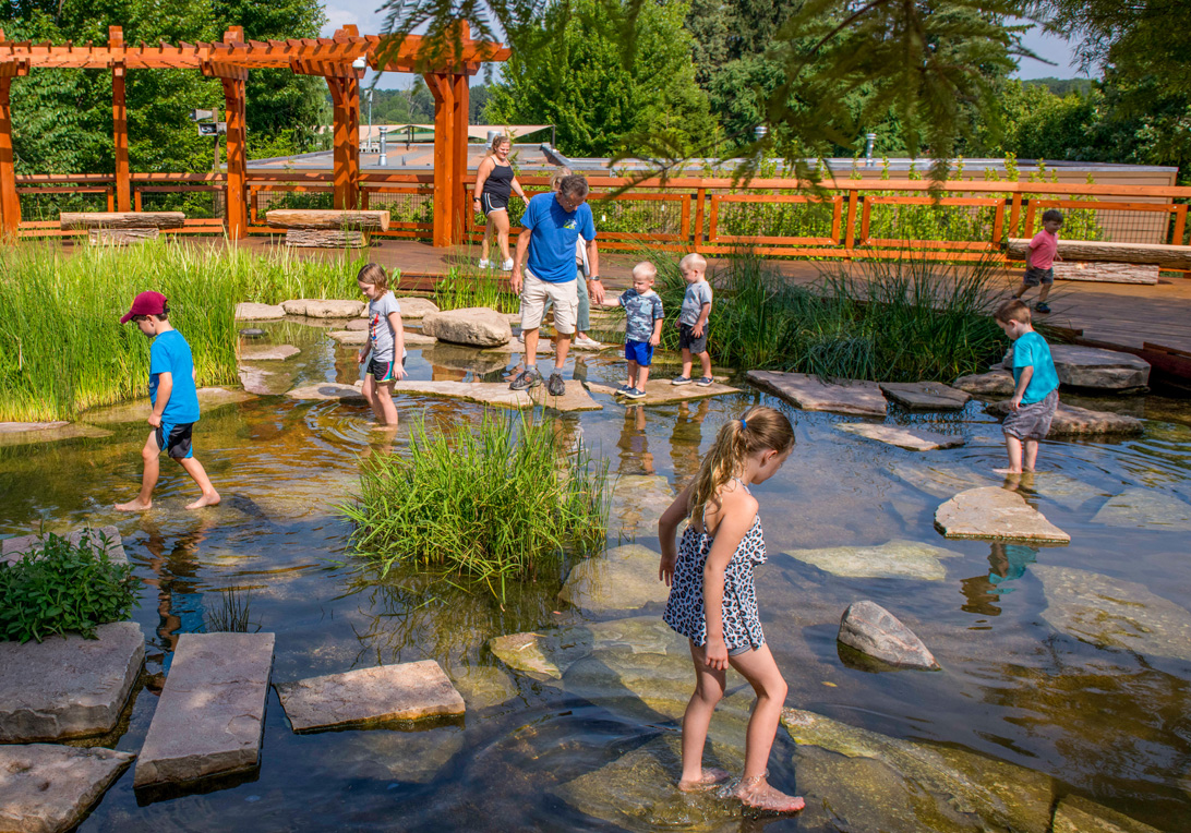 Children and parents play in Wonder Pond while in the Children's Garden
