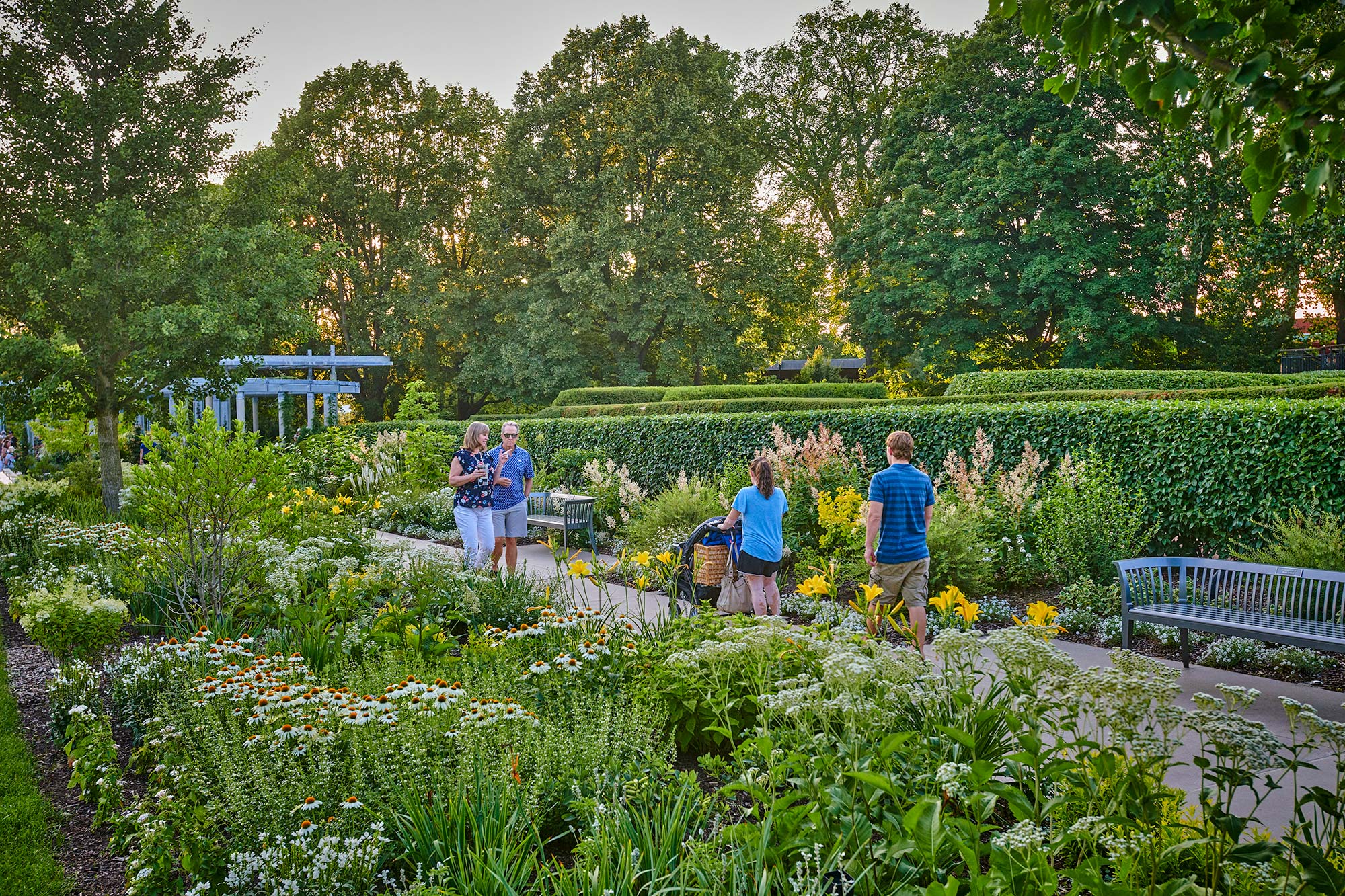 Guests wander through the lush Grand Garden full of flowers on a beautiful summer evening