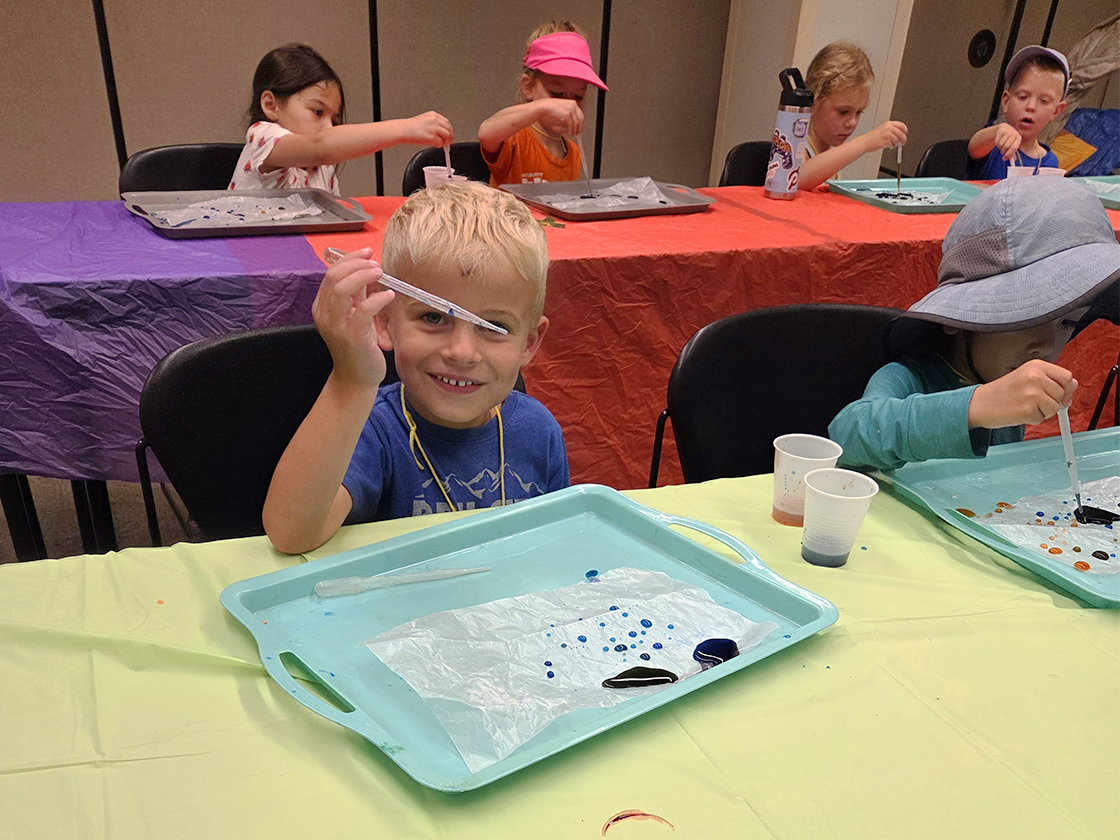 Photograph of a child playing with a pipette during a Summer Science Camp session